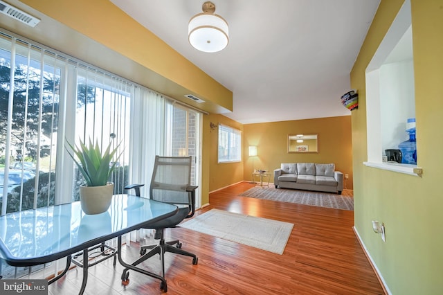 office with hardwood / wood-style floors and a healthy amount of sunlight