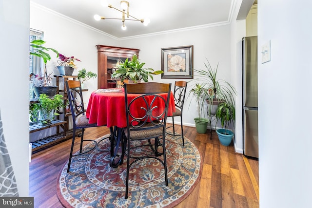 dining room with hardwood / wood-style flooring, ornamental molding, and a chandelier