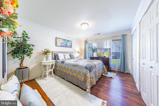 bedroom with a closet, dark hardwood / wood-style flooring, and ornamental molding