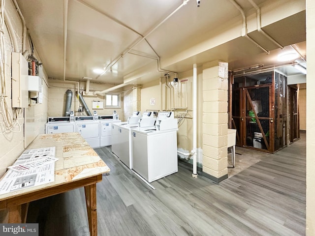 clothes washing area with washing machine and dryer, hardwood / wood-style floors, and electric panel