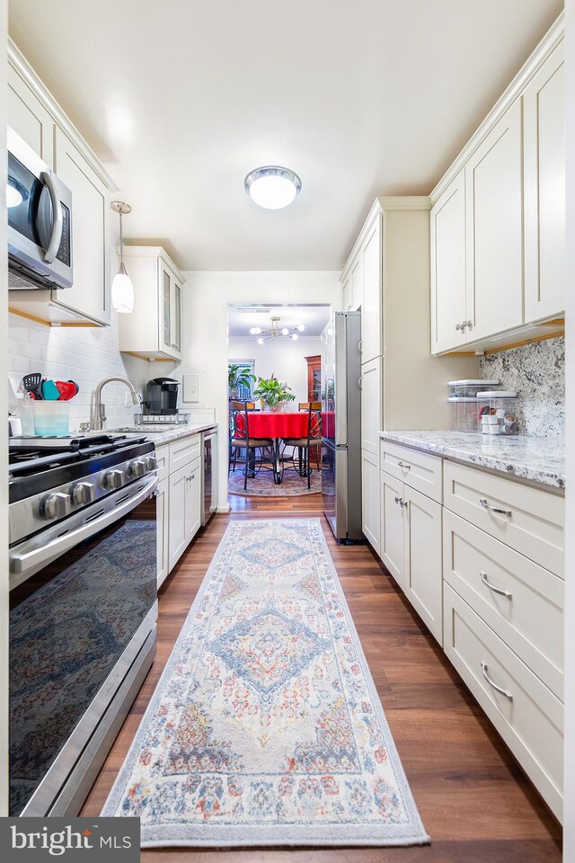 kitchen with decorative backsplash, appliances with stainless steel finishes, dark hardwood / wood-style floors, and white cabinetry