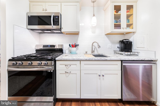 kitchen with light stone countertops, sink, stainless steel appliances, dark hardwood / wood-style flooring, and decorative light fixtures