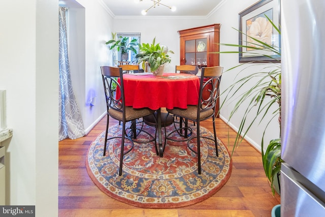 dining room with a notable chandelier, wood-type flooring, and crown molding