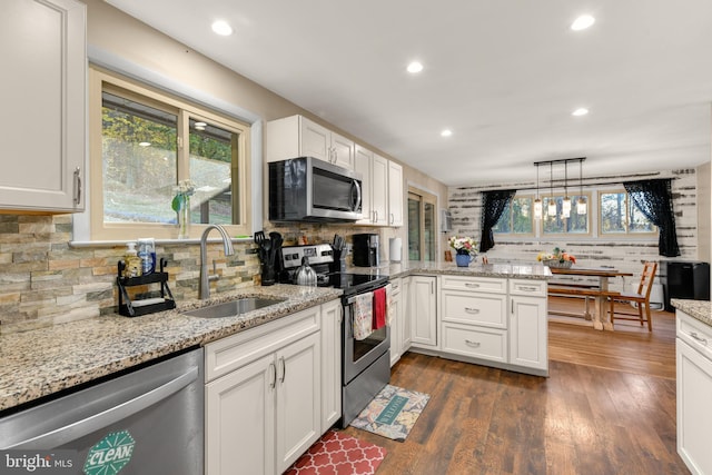 kitchen with sink, stainless steel appliances, dark hardwood / wood-style floors, pendant lighting, and white cabinets