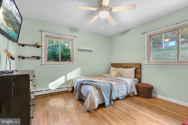 bedroom featuring light hardwood / wood-style flooring, baseboard heating, and ceiling fan