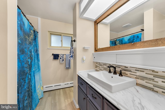 bathroom with backsplash, a skylight, vanity, wood-type flooring, and a baseboard radiator