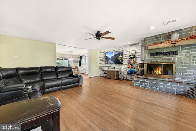 living room featuring hardwood / wood-style floors, a stone fireplace, and ceiling fan