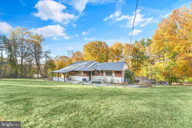 back of property with a lawn, a carport, and a patio