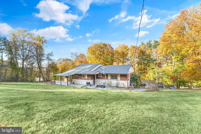 rear view of property with a lawn, a carport, and a patio area