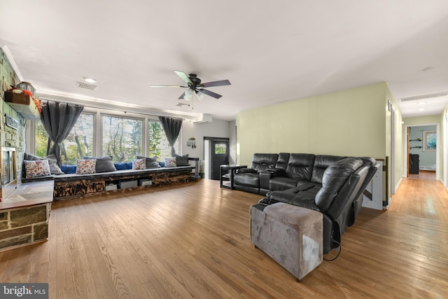 living room featuring light wood-type flooring, ceiling fan, and a baseboard heating unit