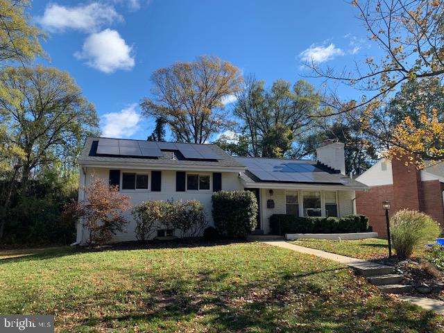 view of front of home with solar panels and a front lawn