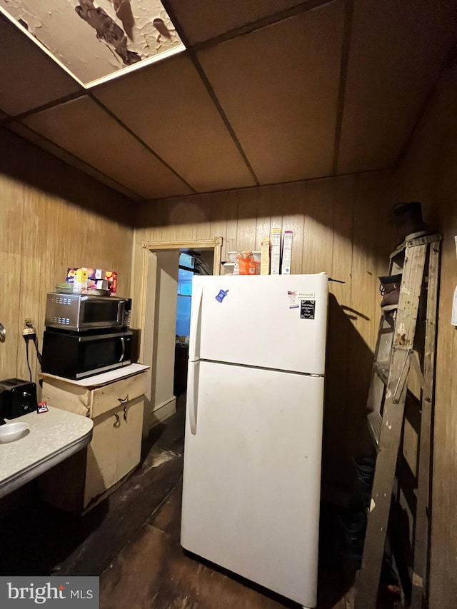 kitchen featuring white refrigerator and wooden walls