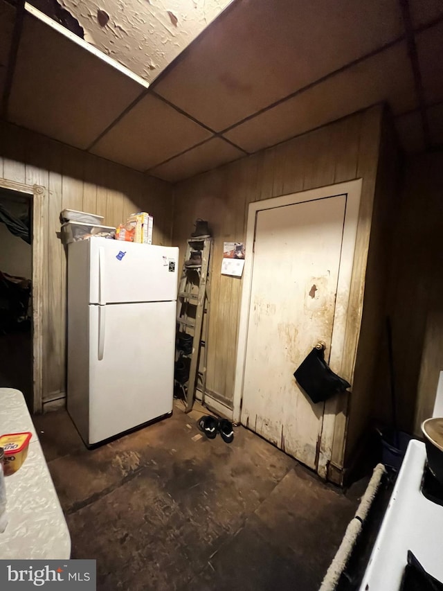 kitchen with a paneled ceiling, white refrigerator, and wooden walls