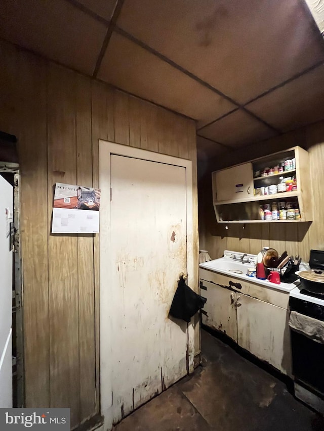 kitchen featuring a drop ceiling, wooden walls, and sink