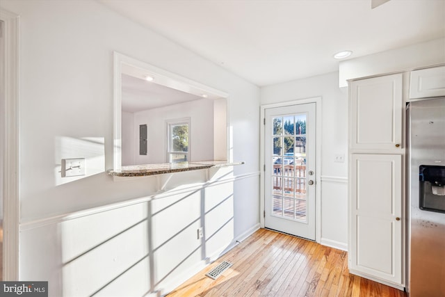 kitchen featuring white cabinets, light wood-type flooring, and stainless steel refrigerator with ice dispenser