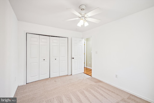 unfurnished bedroom featuring light carpet, a closet, and ceiling fan