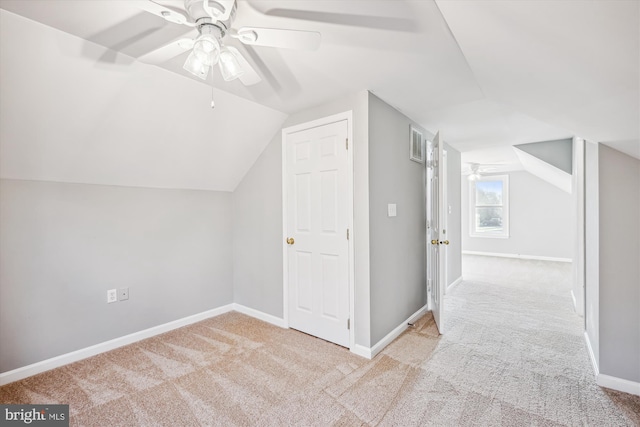 additional living space with ceiling fan, light colored carpet, and vaulted ceiling