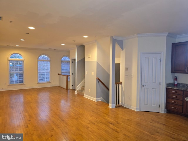 unfurnished living room with light wood-type flooring and crown molding