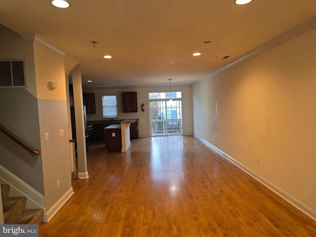 unfurnished living room featuring wood-type flooring and crown molding