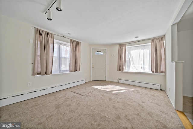 spare room with light carpet, track lighting, and baseboard heating