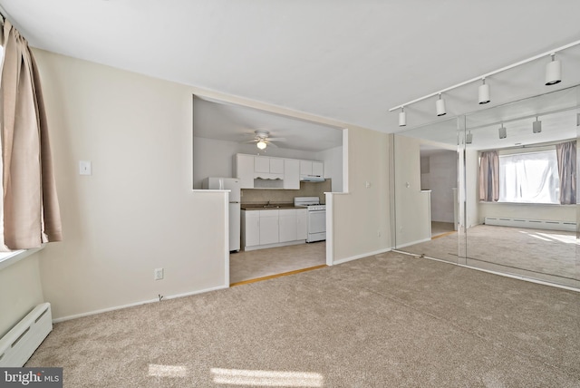 carpeted empty room featuring ceiling fan, a baseboard radiator, and track lighting