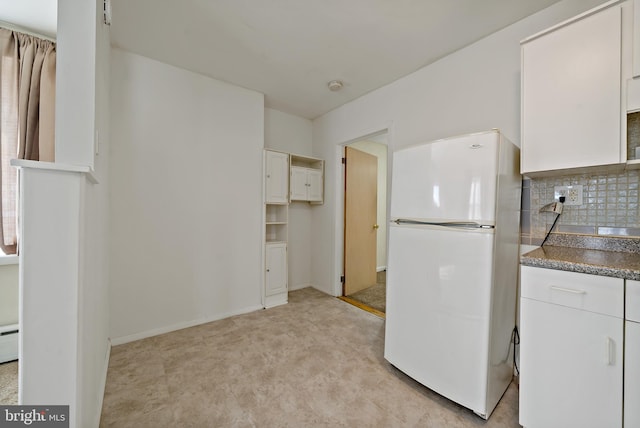 kitchen with white refrigerator, white cabinetry, and backsplash