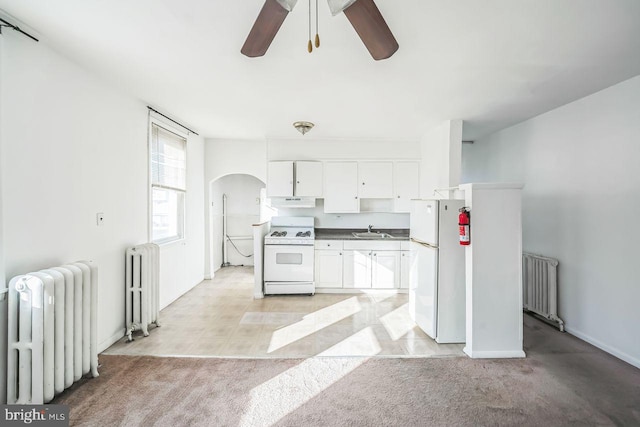 kitchen with white appliances, white cabinetry, and radiator