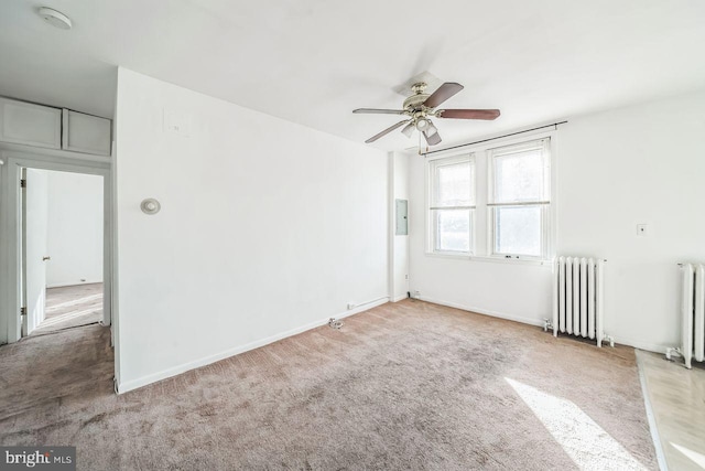 carpeted spare room with radiator, ceiling fan, and electric panel