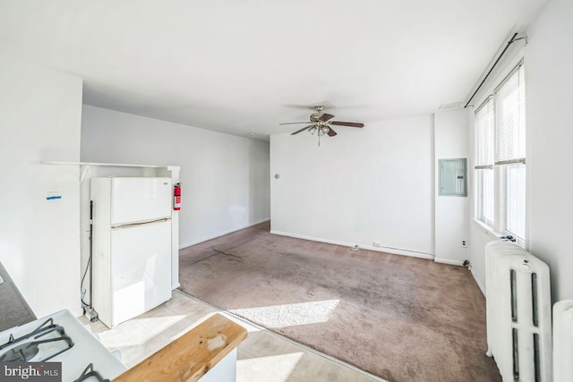 interior space with electric panel, light colored carpet, radiator, and ceiling fan