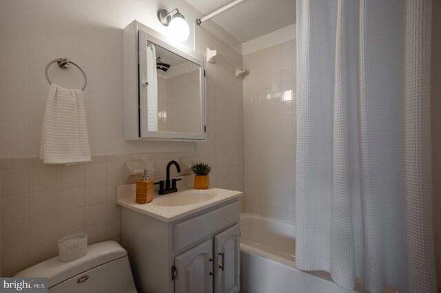 full bathroom featuring vanity, toilet, tile walls, and shower / bath combo with shower curtain