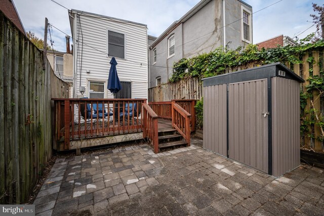 rear view of house featuring a patio area, a shed, and a deck