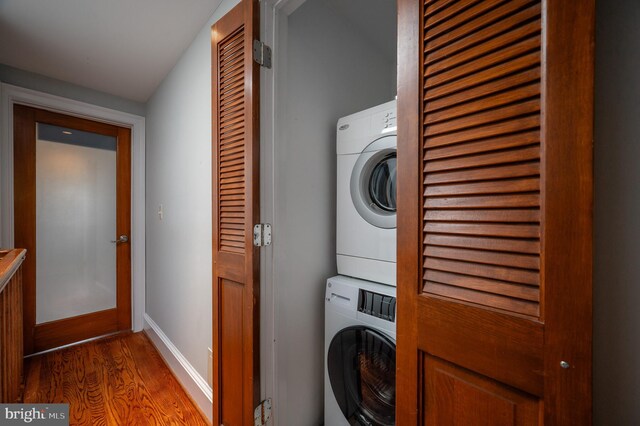 washroom featuring stacked washer / dryer and wood-type flooring