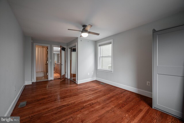 unfurnished bedroom with ceiling fan and dark wood-type flooring