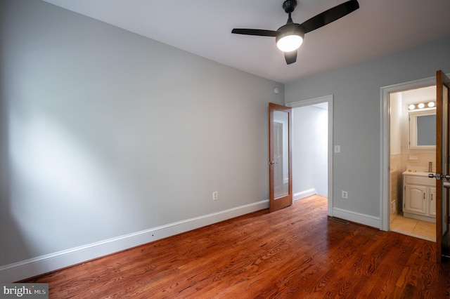 unfurnished bedroom featuring ensuite bath, ceiling fan, and dark hardwood / wood-style floors