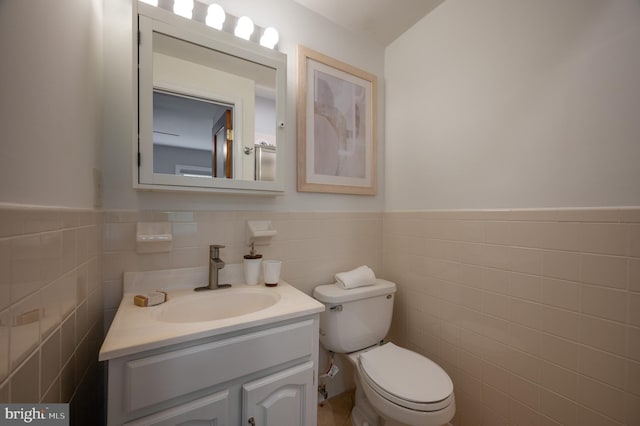 bathroom featuring vanity, toilet, and tile walls