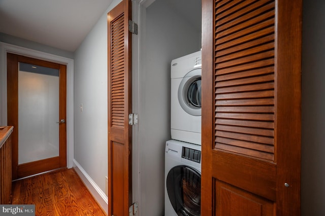 laundry room featuring hardwood / wood-style floors and stacked washer and dryer