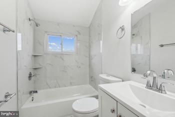 full bathroom with vanity, tiled shower / bath combo, and toilet