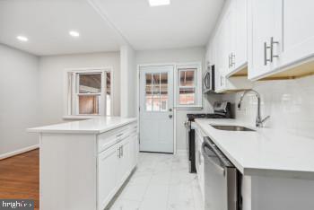 kitchen with white cabinets, appliances with stainless steel finishes, a kitchen island, and sink