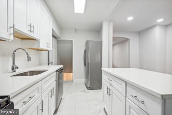 kitchen featuring appliances with stainless steel finishes, white cabinetry, and sink