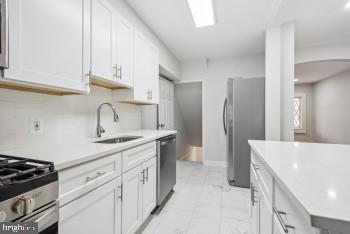 kitchen featuring white cabinets, decorative backsplash, sink, and stainless steel appliances