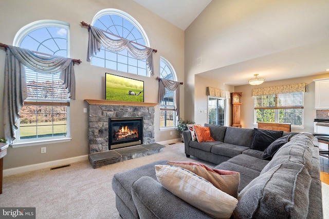 carpeted living room featuring a fireplace, high vaulted ceiling, and plenty of natural light