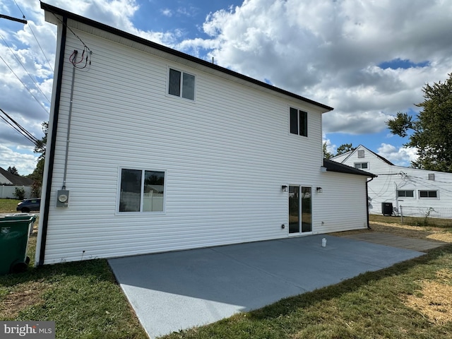 back of property featuring cooling unit, a lawn, and a patio area