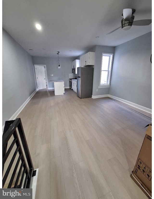 unfurnished living room with ceiling fan and light wood-type flooring