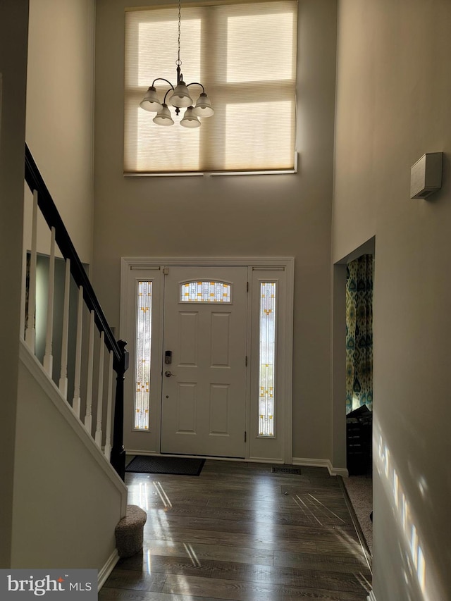 foyer featuring a towering ceiling, dark hardwood / wood-style flooring, and a chandelier