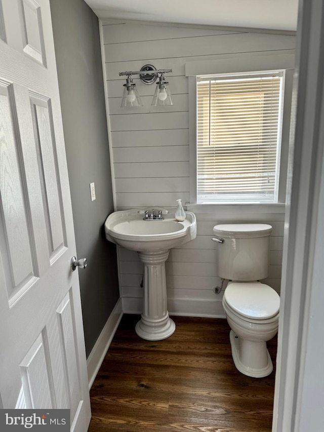 bathroom with hardwood / wood-style floors, toilet, and wooden walls