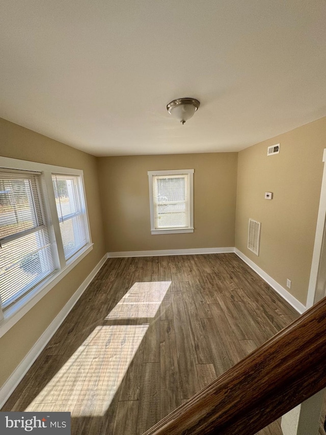 spare room featuring dark hardwood / wood-style floors and a healthy amount of sunlight