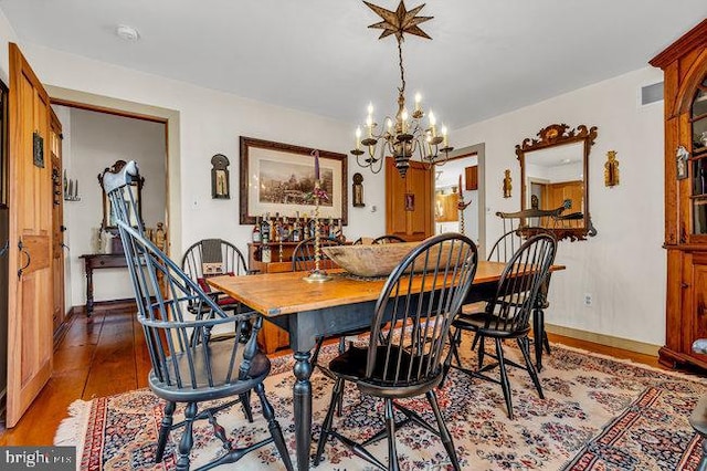 dining area with hardwood / wood-style floors and an inviting chandelier