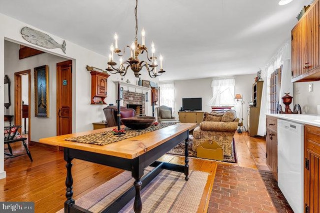 dining space with a fireplace, wood-type flooring, and an inviting chandelier