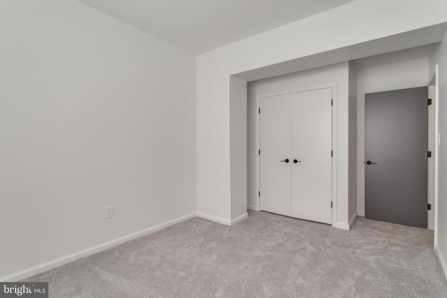 unfurnished bedroom featuring light carpet and a closet