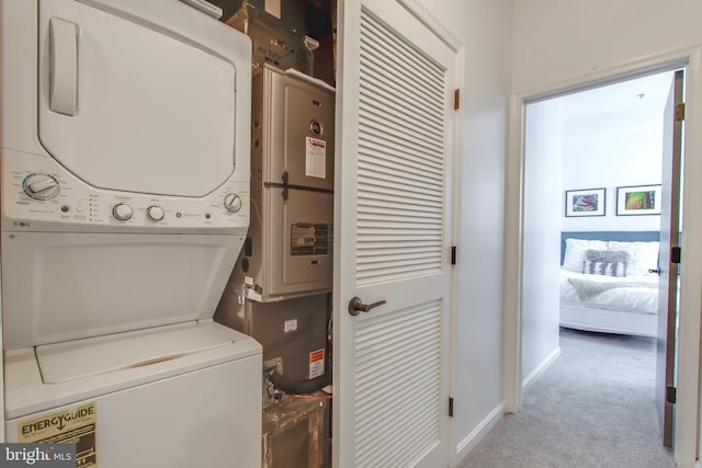 clothes washing area featuring light carpet and stacked washer and clothes dryer